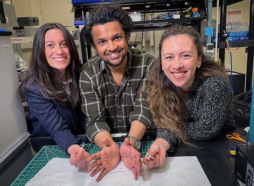 Three scientists holding a fiber in a lab.