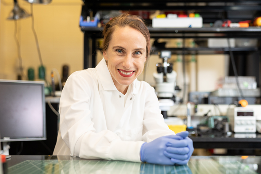 Woman sitting with hands folded on lab bench.