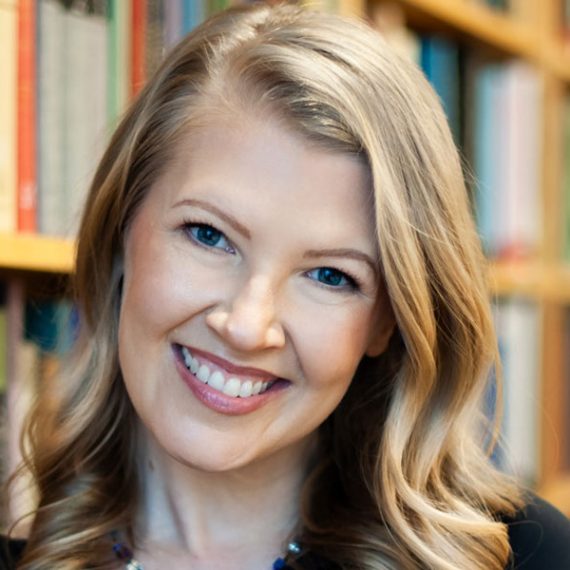 Woman smiling at camera in front of bookcase.